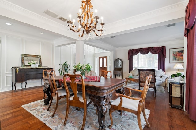 dining space featuring dark wood-style floors, visible vents, a decorative wall, and ornamental molding