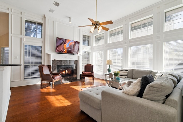 living area featuring dark wood-style floors, a wealth of natural light, visible vents, and a fireplace