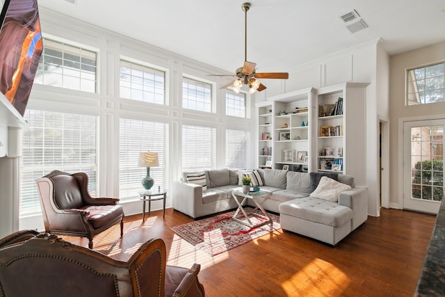 interior space with visible vents, ceiling fan, a high ceiling, and wood finished floors