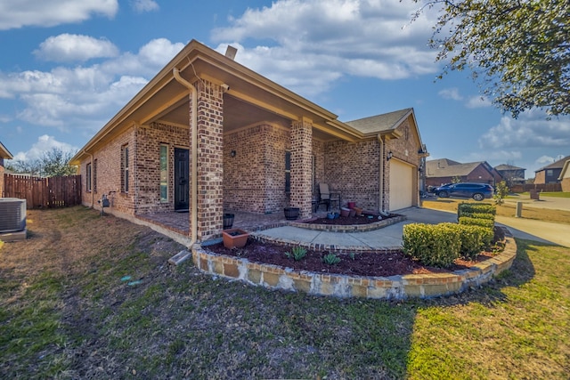 view of home's exterior featuring a garage, brick siding, central AC, and fence