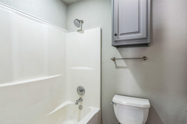 bathroom featuring toilet, a textured wall, and shower / bathtub combination