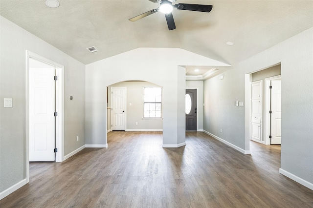 unfurnished living room with arched walkways, dark wood-style flooring, vaulted ceiling, and baseboards