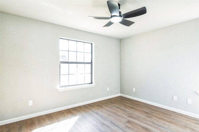 empty room with wood finished floors, a ceiling fan, and baseboards