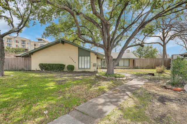 view of front of house featuring fence, a front lawn, and brick siding