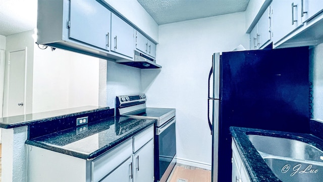 kitchen featuring white cabinets, stainless steel appliances, a textured ceiling, light wood-style floors, and a sink