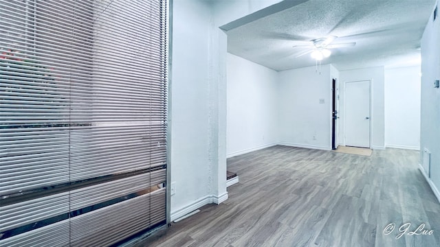 unfurnished room featuring ceiling fan, a textured ceiling, baseboards, and wood finished floors