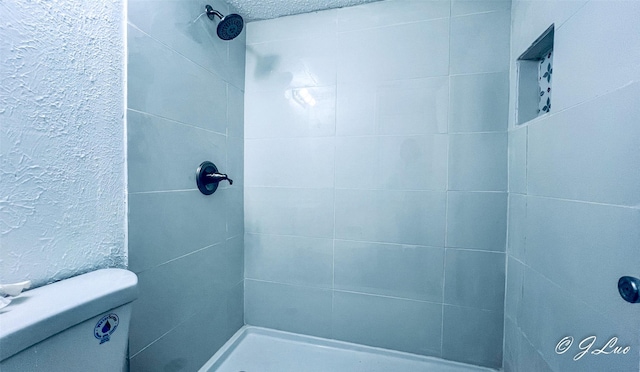 full bathroom with a tile shower and a textured wall