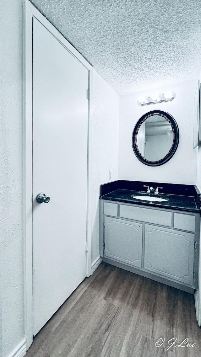 bathroom featuring a textured ceiling, vanity, and wood finished floors