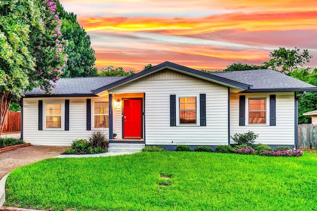 single story home featuring a shingled roof, fence, and a yard