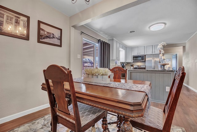 dining room featuring wood finished floors, visible vents, and baseboards