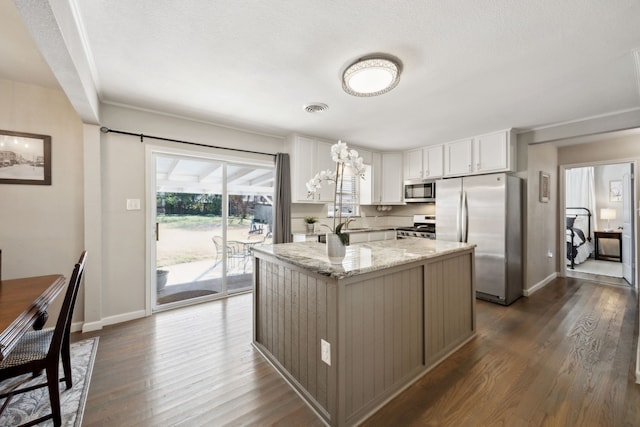 kitchen with light stone counters, visible vents, white cabinets, appliances with stainless steel finishes, and dark wood-style floors