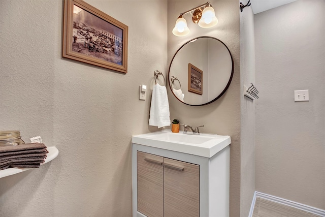 bathroom with a textured wall, vanity, and baseboards