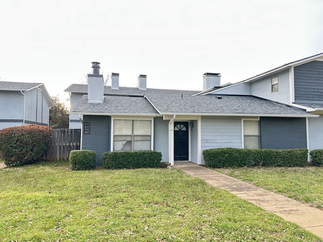 view of front of home with roof with shingles, a chimney, fence, and a front yard