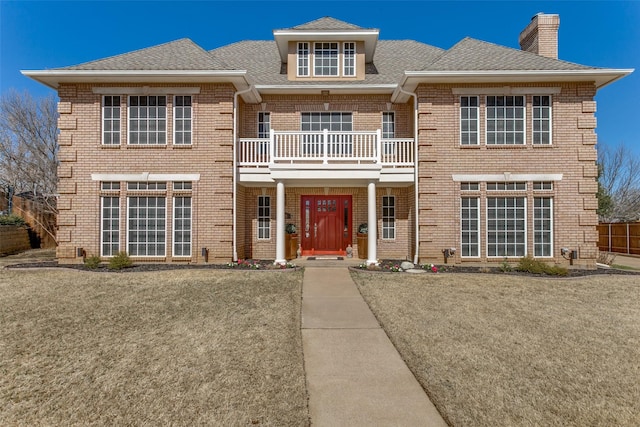 view of front of home with roof with shingles, brick siding, and a chimney