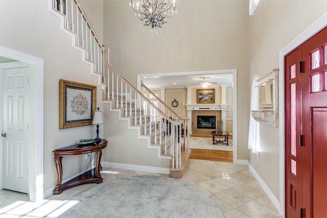 entryway with light tile patterned floors, a high ceiling, stairway, and a glass covered fireplace