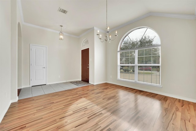 spare room featuring light wood finished floors, visible vents, lofted ceiling, an inviting chandelier, and crown molding