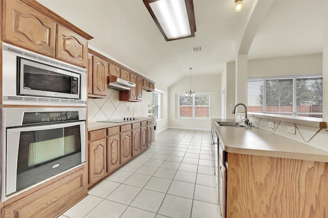 kitchen featuring light tile patterned floors, under cabinet range hood, stainless steel appliances, a sink, and visible vents