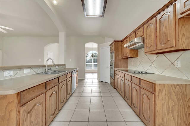 kitchen featuring light tile patterned floors, lofted ceiling, appliances with stainless steel finishes, a sink, and under cabinet range hood