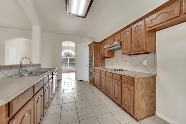 kitchen with black electric stovetop, under cabinet range hood, a sink, vaulted ceiling, and tasteful backsplash