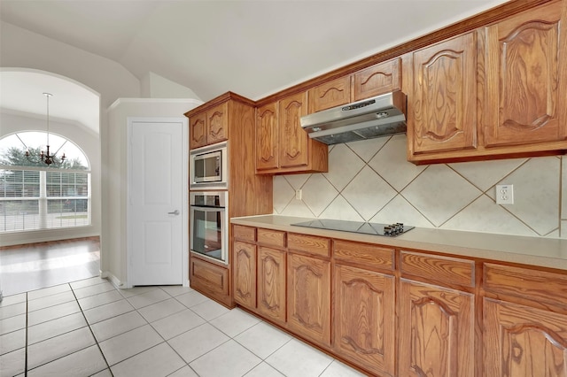 kitchen with light tile patterned floors, lofted ceiling, appliances with stainless steel finishes, light countertops, and under cabinet range hood