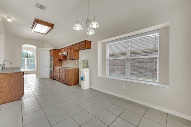 kitchen featuring light tile patterned floors, a sink, vaulted ceiling, light countertops, and tasteful backsplash