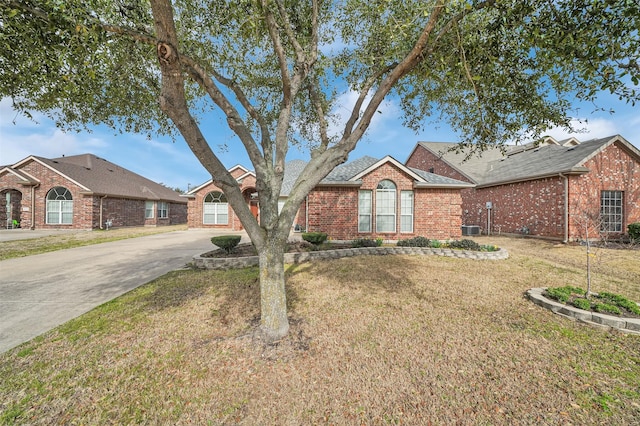 view of front of house with concrete driveway, brick siding, and a front lawn