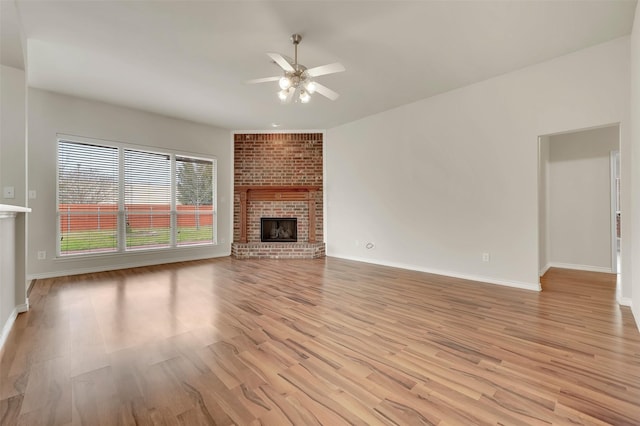 unfurnished living room featuring light wood-type flooring, a fireplace, a ceiling fan, and baseboards