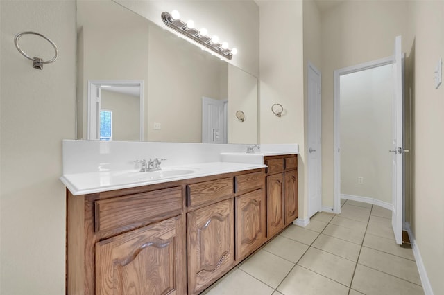 bathroom with double vanity, tile patterned flooring, baseboards, and a sink