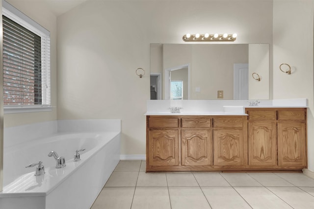 bathroom with double vanity, a garden tub, baseboards, and tile patterned floors