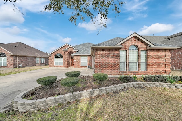 view of front of home with roof with shingles, concrete driveway, and brick siding