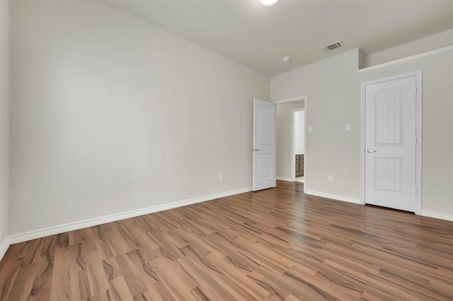 spare room featuring visible vents, baseboards, and wood finished floors