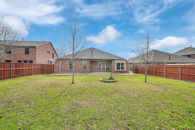 rear view of property with a yard, a fenced backyard, a patio, and brick siding