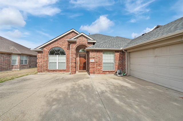 view of front of home featuring driveway, brick siding, roof with shingles, and an attached garage