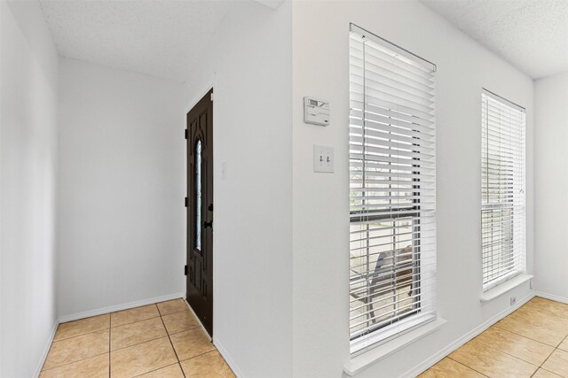 hallway featuring tile patterned floors, baseboards, and a textured ceiling