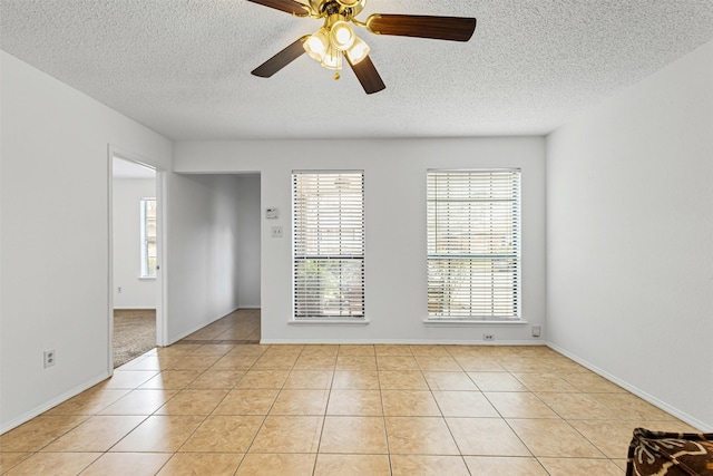 spare room with light tile patterned floors, baseboards, a textured ceiling, and ceiling fan