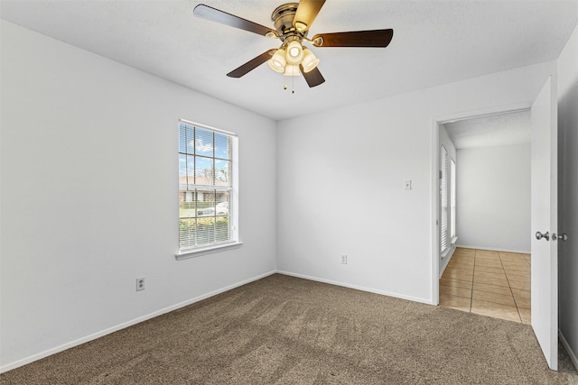 unfurnished room with baseboards, carpet floors, ceiling fan, and tile patterned flooring