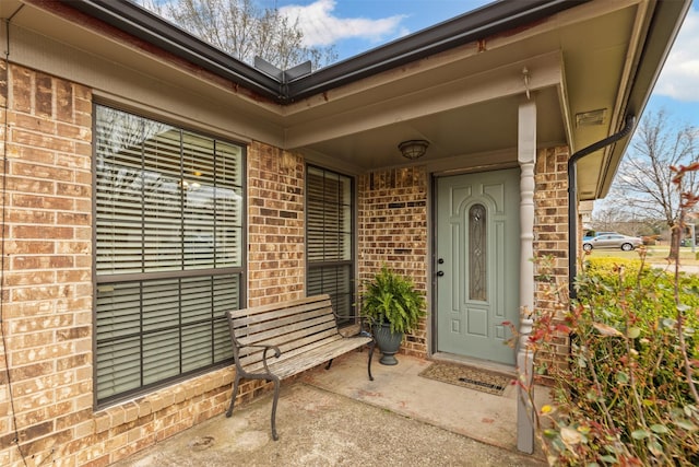 doorway to property featuring brick siding and a porch