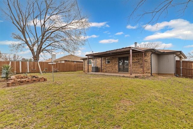 rear view of property with central AC unit, french doors, a lawn, a patio area, and brick siding