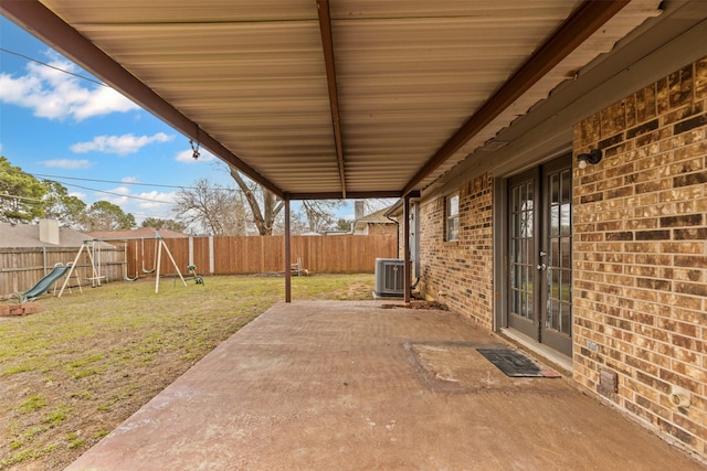 view of patio / terrace featuring central AC unit, french doors, a playground, and a fenced backyard