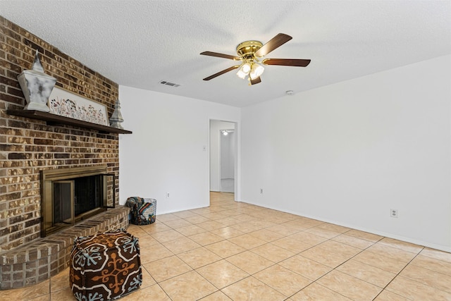 unfurnished living room with tile patterned floors, visible vents, a brick fireplace, and a textured ceiling