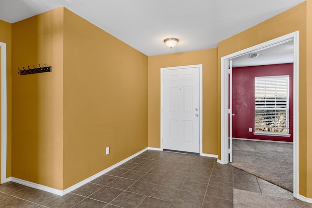 entrance foyer with dark tile patterned flooring, dark carpet, visible vents, and baseboards