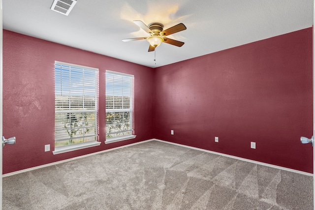 empty room featuring carpet, visible vents, a textured wall, ceiling fan, and baseboards