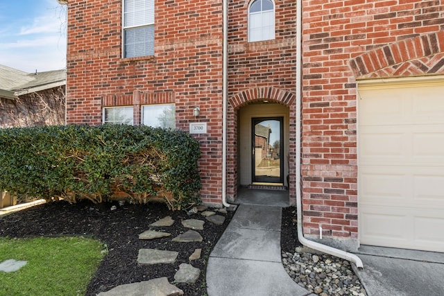 property entrance with an attached garage and brick siding