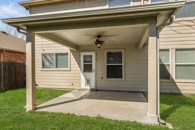 entrance to property featuring a yard, fence, a ceiling fan, and a patio