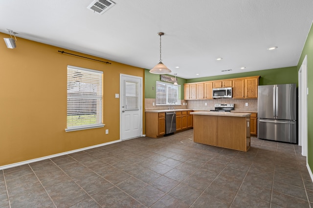 kitchen featuring stainless steel appliances, a kitchen island, visible vents, light countertops, and tasteful backsplash