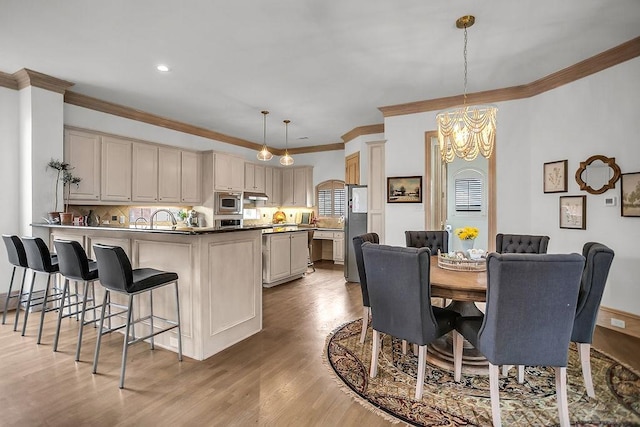 dining area with light wood-style flooring, ornamental molding, and a chandelier