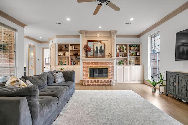 living area featuring crown molding, a brick fireplace, light wood-style flooring, and recessed lighting