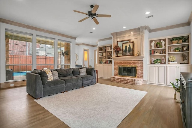 living area featuring recessed lighting, visible vents, ornamental molding, a brick fireplace, and wood finished floors