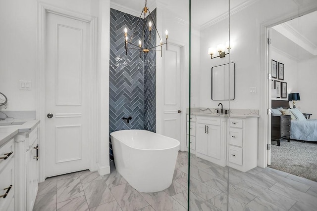 ensuite bathroom with two vanities, marble finish floor, a freestanding bath, crown molding, and a sink