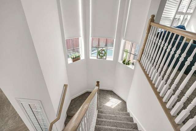 staircase with baseboards, visible vents, and carpet flooring